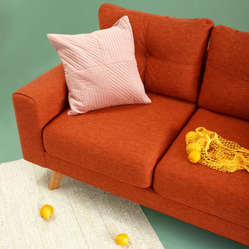 A cosy terracotta sofa with a quilted pillow set up for an unhurried evening